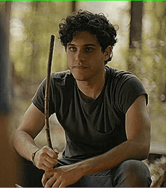 a man with curly hair is holding a stick in his hands