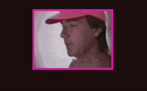 a shirtless man in a red hat is standing in front of a pink frame with the words `` absolutely '' written on it .