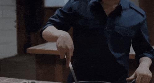 a man in a blue shirt is cutting something