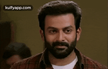 a man with a beard is wearing a plaid shirt and smiling .