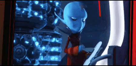 a blue alien in a red suit is using a computer .
