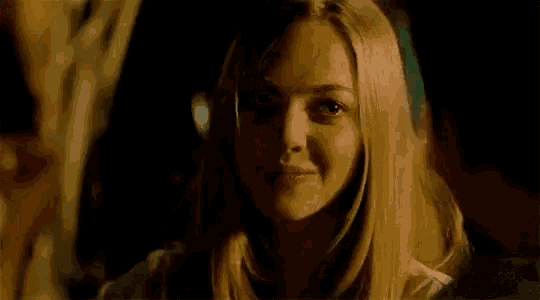 a woman is smiling at a man in a dark room in a movie .