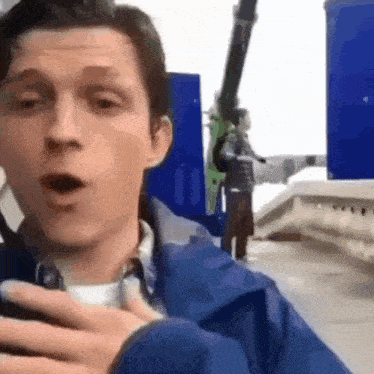a man in a blue jacket is standing in front of a blue box .