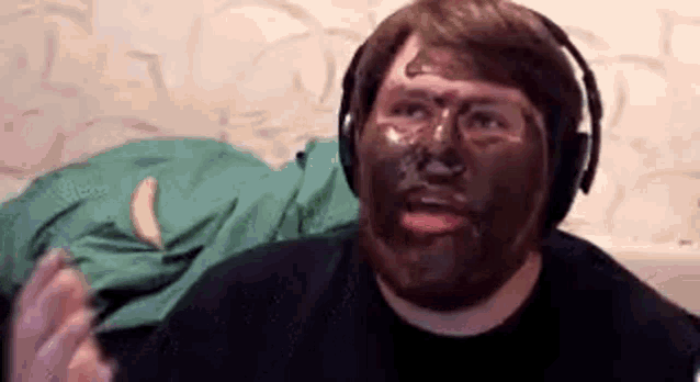 a man with a beard is wearing headphones and has a chocolate mask on his face .