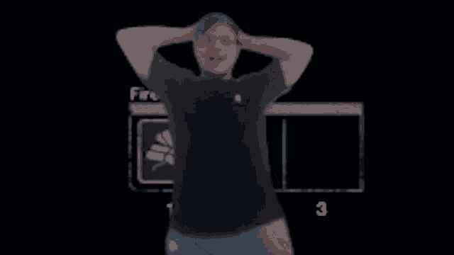 a man in a black shirt and blue shorts is standing in front of a black screen .