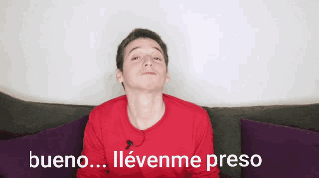 a man in a red shirt is sitting on a couch with the words bueno written in white