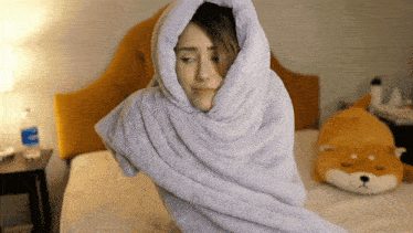 a woman wrapped in a blanket with a bottle of aquafina water behind her