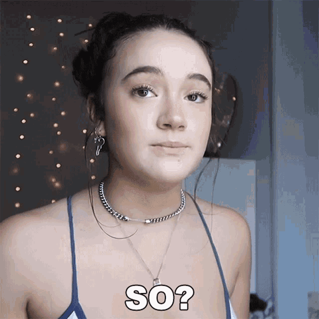 a woman wearing a blue tank top and a necklace says so