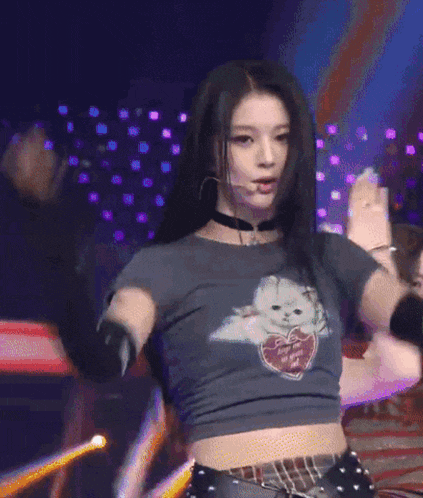 a woman in a choker is dancing on a stage with a purple background .
