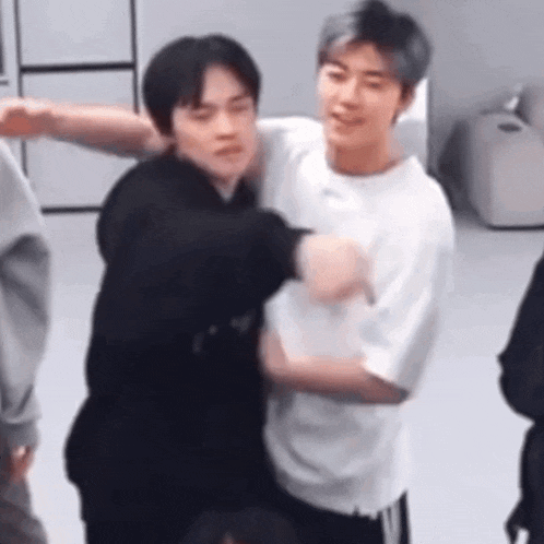 two men are hugging each other in a room while standing next to each other .