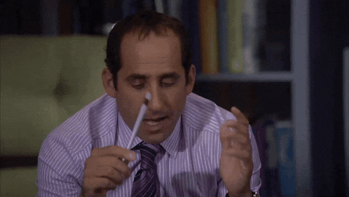 a man in a striped shirt and tie holds a pen to his mouth