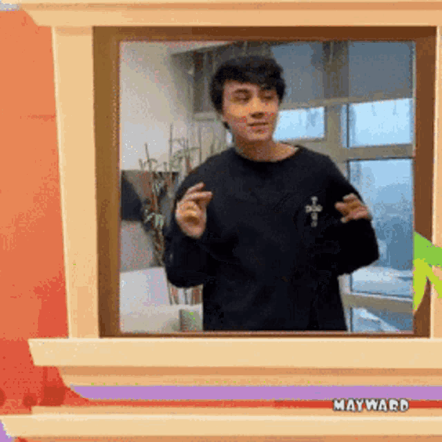 a man in a black shirt is standing in front of a window with the word mayward on it