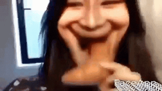 a woman is making a funny face with her hands while holding a balloon in her mouth .