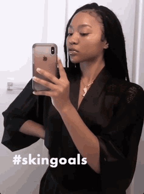 a woman in a black robe is taking a picture of herself in a mirror with the hashtag #skingoals