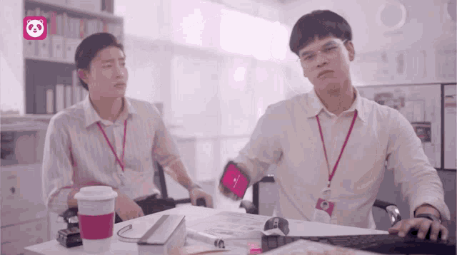 two men are sitting at a desk with a panda icon in the corner