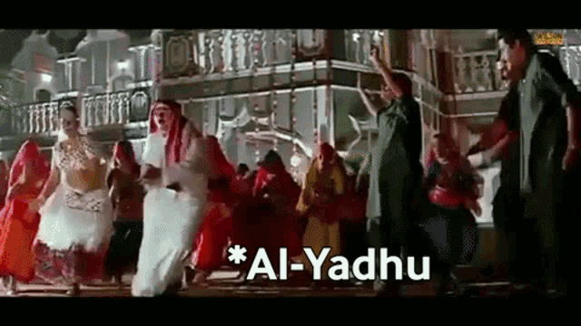 a group of people are dancing in front of a building with the words `` al-yadhu '' written on the bottom .