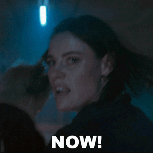 a woman in a dark room with the word now on the bottom