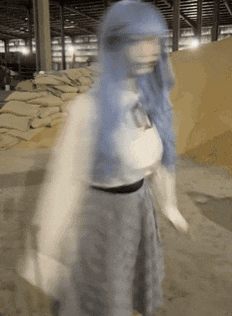 a woman with blue hair stands in front of a pile of sandbags
