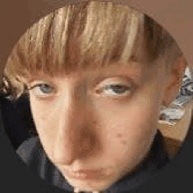 a close up of a person 's face with a shaved head and bangs .