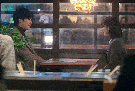 a man and a woman are sitting at a table looking at each other