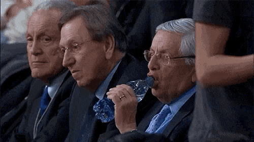 a man drinking water from a plastic bottle in a crowd of people