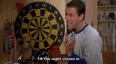 a man is talking on a cell phone in front of a dartboard .