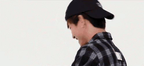 a man wearing a plaid shirt and a baseball cap is standing in front of a white background .