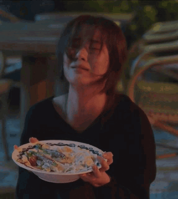a woman is holding a plate of food in her hands and making a face .