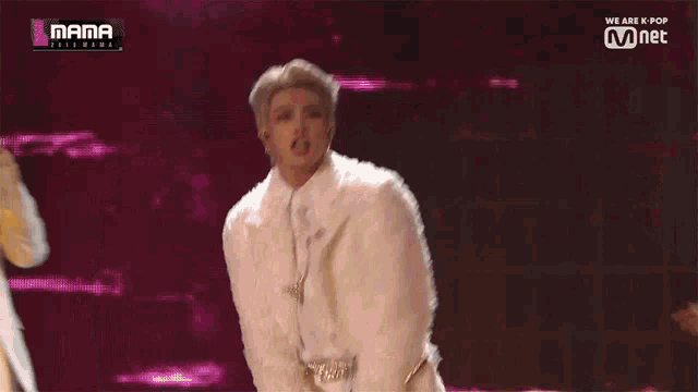 a man in a white fur coat is singing into a microphone
