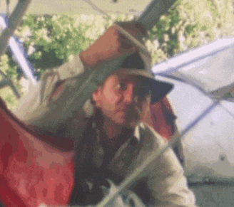 a man wearing a hat is sitting in a hammock .