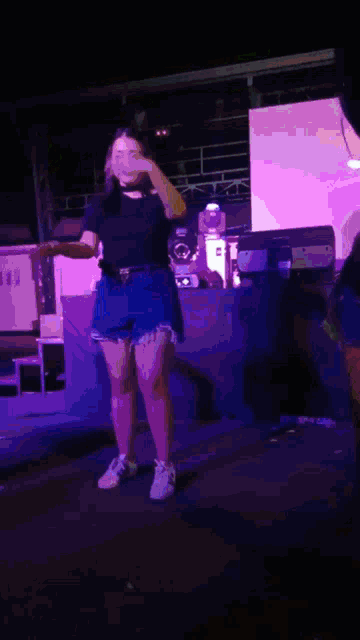 a woman in a black shirt and shorts is dancing on a stage