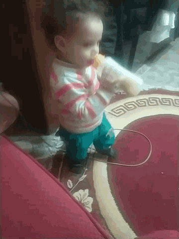 a baby is drinking from a bottle on a rug with a greek key pattern