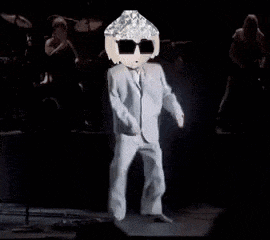a man in a suit and sunglasses is dancing on stage .