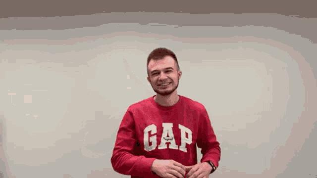 a man wearing a red gap sweater is smiling