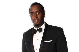 a man in a tuxedo with a bow tie is standing in front of a white background .