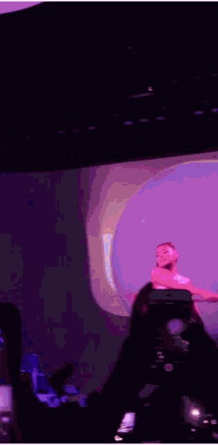 a man is standing on a stage in front of a purple background .