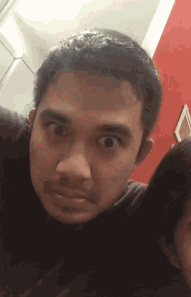 a man with a beard looks at the camera with his eyes wide open