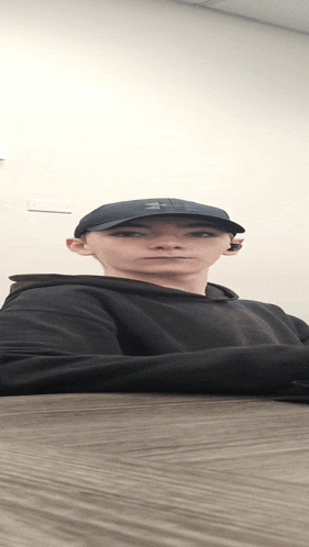 a man wearing a black hat and a black sweatshirt looks at the camera