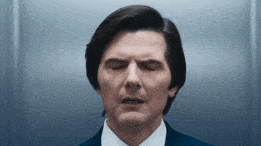 a man with his eyes closed is wearing a suit