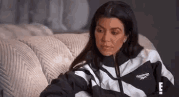a woman is sitting on a couch wearing a jacket .