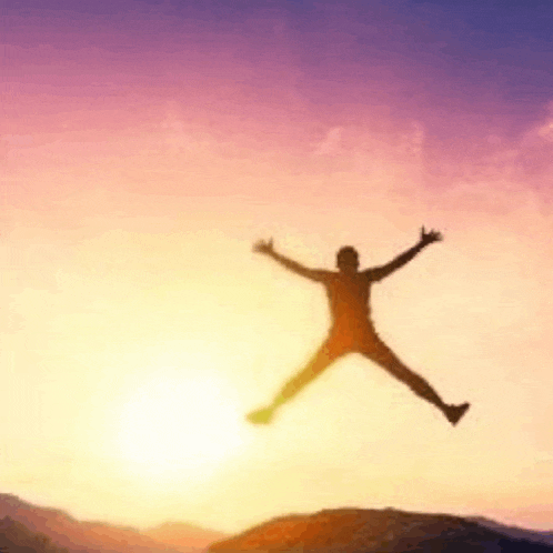 a silhouette of a man jumping in the air with his arms outstretched at sunset .