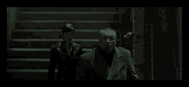 a man and a woman are standing next to each other in a dark room in a movie .
