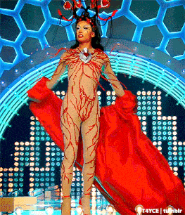 a woman in a red costume is standing on a stage in front of a chandelier ..