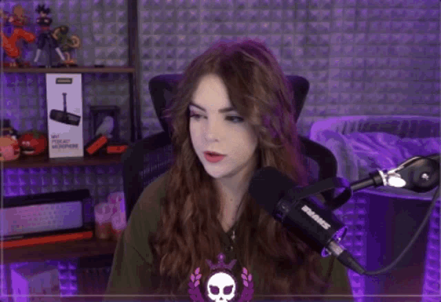 a woman is talking into a shure microphone in a purple room