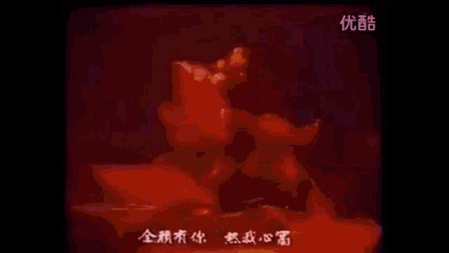 a man is singing into a microphone with chinese writing on the screen behind him .