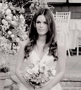 a woman in a white dress holds a bouquet of flowers