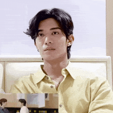 a man wearing a yellow shirt is sitting in a chair