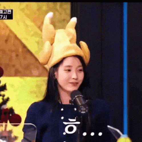 a woman is wearing a chicken hat and talking into a microphone .