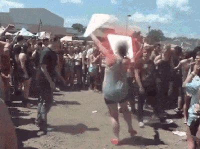 a woman is dancing in front of a crowd of people while holding a sign .