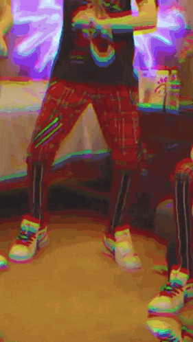 a person wearing red plaid pants and white sneakers is standing in a room with a purple light behind them .